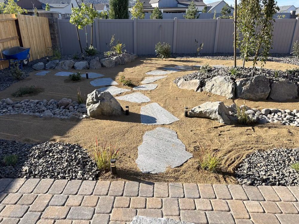 Cut flagstone stepping pads leading through decomposed granite and boulders to a paver patio